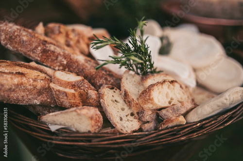 The board is set up on a long buffet table. The cheeses are arranged alongside sliced cured meats, fresh grapes, and berries, and the warm glow of the overhead lights adds to the overall ambiance 