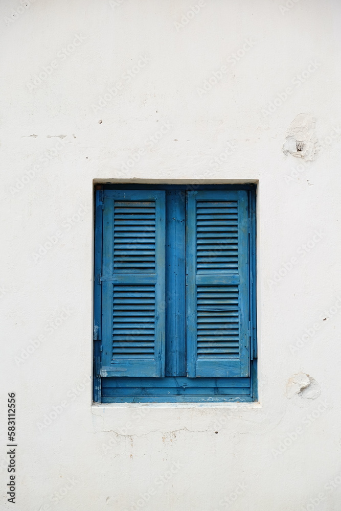 Blue window shutters on white wall