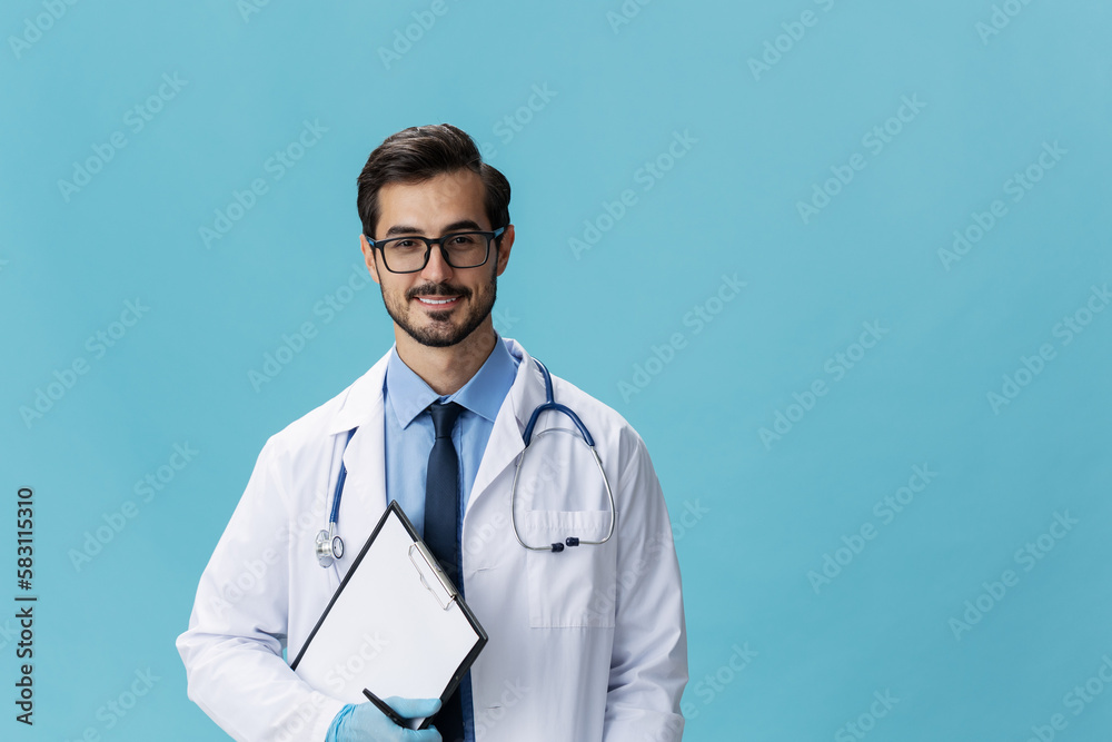 Male doctor in a white coat and glasses with a medical record on a blue isolated background, copy space, space for text Male doctor in a white coat and glasses with a medical record on a blue isolated background, copy space, space for text