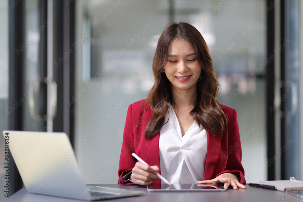 Young beautiful asian businesswoman in office working with laptop using tablet to work with electronic documents. Young beautiful asian businesswoman in office working with laptop using tablet to work with electronic documents.