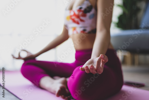 Beautiful asian woman doing relaxing exercise at home and practicing yoga in quiet living room.