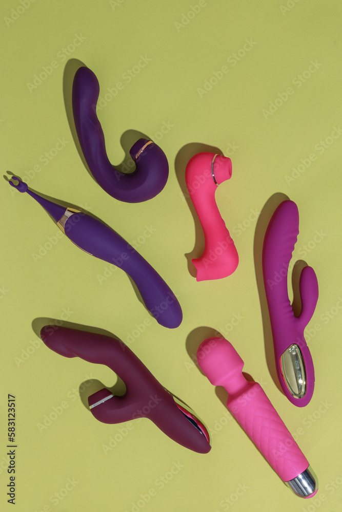 Obraz premium A lot of different dildo vibrators on yellow background with shadows. Sex toy for adult