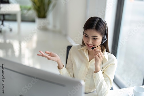 Portrait of happy smiling female customer support phone operator at workplace. Smiling beautiful Asian woman working in call center