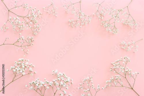 Top view of small white gypsophila flowers over pastel pink background