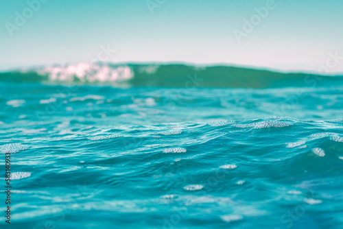 Seawater view with focus on the front of the water. Blurred background with low depth of field. Template on the theme of a seaside vacation with blank space for text.