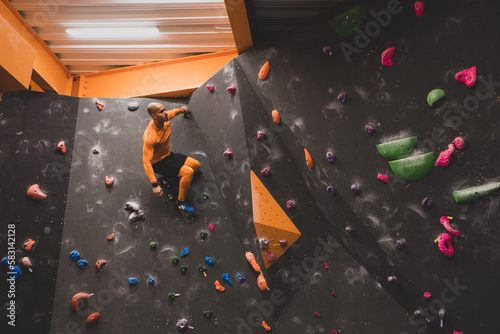 African American male rock climber climbing a bouldering wall photo