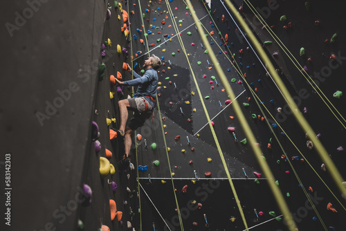 Mature male rock climber climbing an indoor climbing wall  photo
