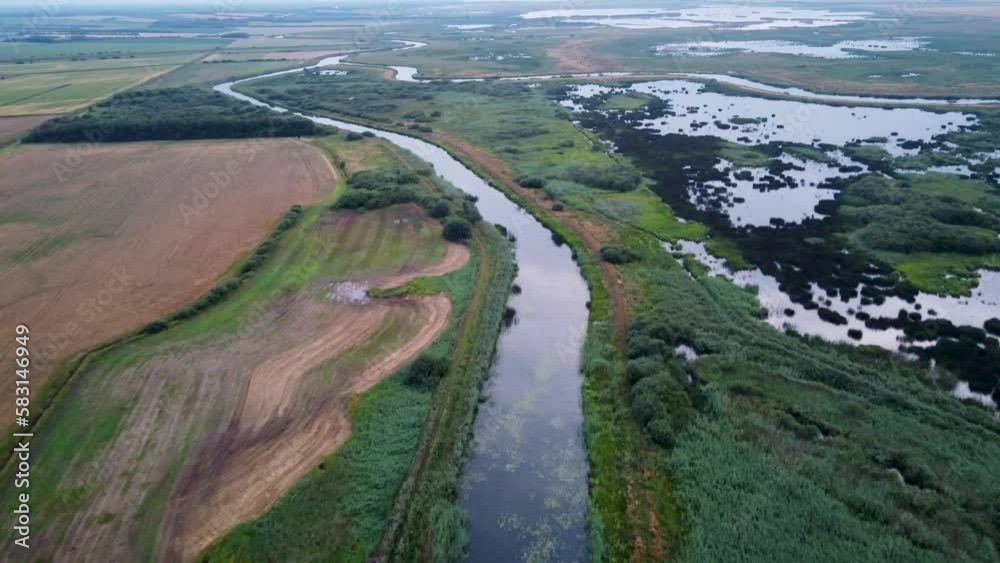 Aerial of a water stream with a wide green field in the background on Romo Denmark Aerial of a water stream with a wide green field in the background on Romo Denmark