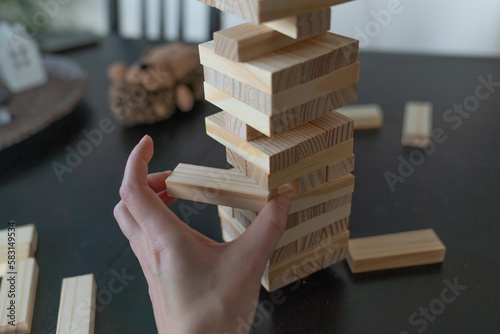 Adult hand pulling a wooden block from a tower