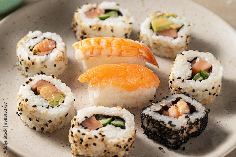 Closeup homemade sushi rolls with salmon, shrimp, avocado i n a round plate