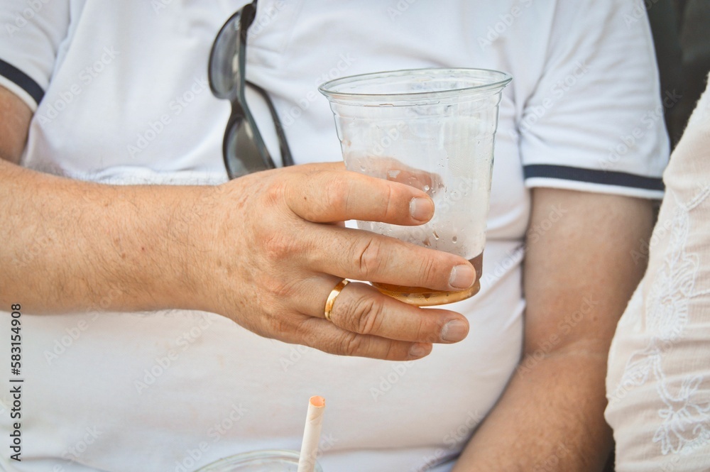 Closeup shot of a male's hand with a marriage ring and a plastic cup of soda Closeup shot of a male's hand with a marriage ring and a plastic cup of soda