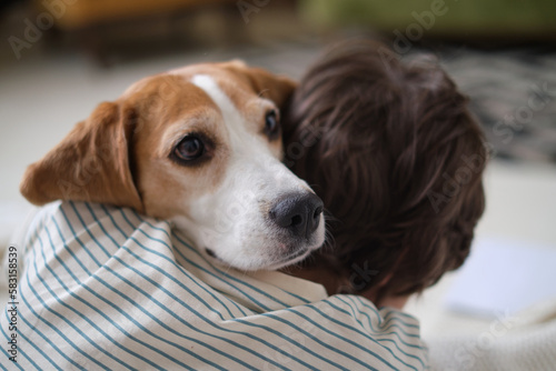 boy and faithful beagle sharing a loving embrace in a charming snapshot. Picture perfect moment of a dog lover cuddling with his furry companion, radiating happiness © yavdat