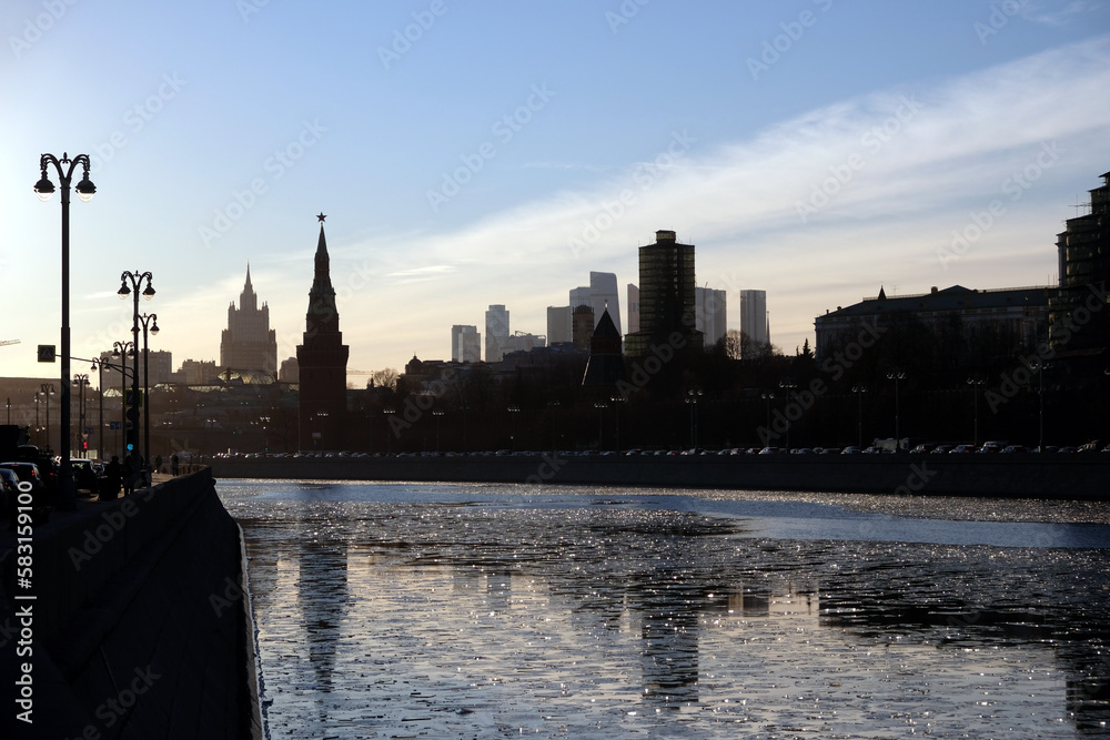 Obraz premium Moscow river, embankment and silhouettes of buildings and Kremlin towers under clear cloudless sky