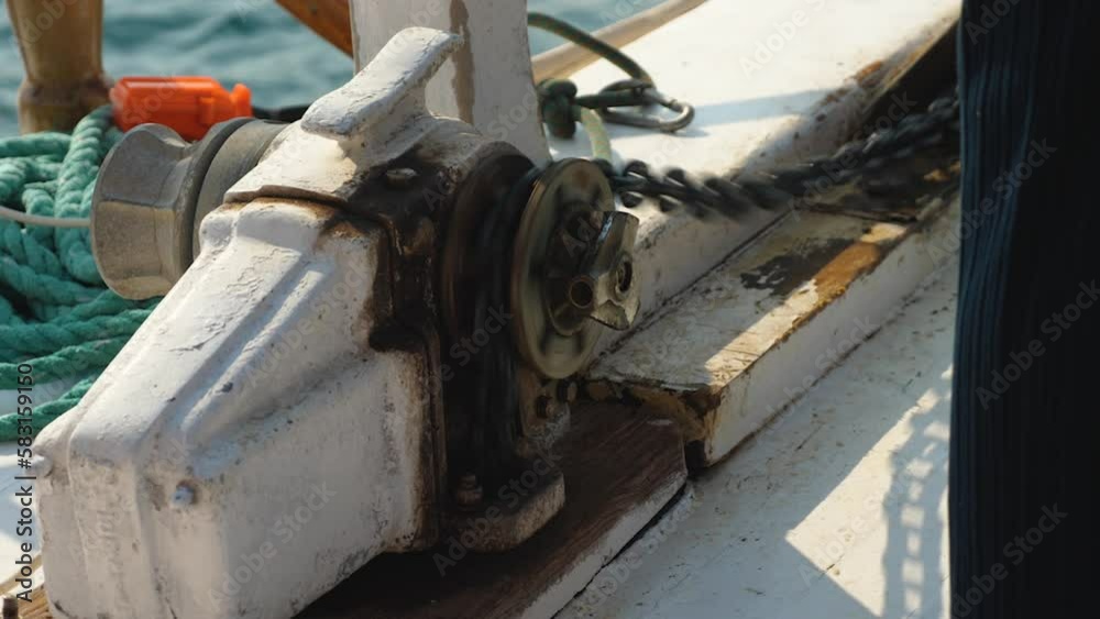 Close-up of anchor chain sliding on tensioning pulley while anchor is lowered. The hand turns the mechanism and the chain unwinding stops. Shipboard equipment. Summer vacation at sea. Slow motion Close-up of anchor chain sliding on tensioning pulley while anchor is lowered. The hand turns the mechanism and the chain unwinding stops. Shipboard equipment. Summer vacation at sea. Slow motion