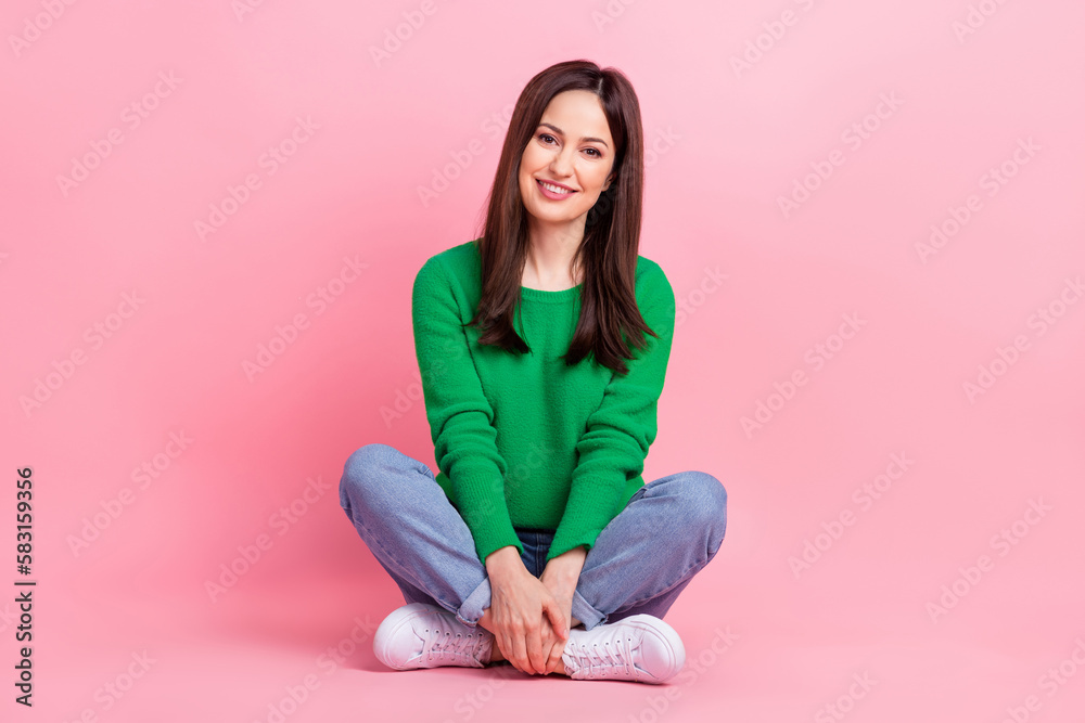 Full length photo of pretty funny lady dressed green pullover sitting legs crossed isolated pink color background Full length photo of pretty funny lady dressed green pullover sitting legs crossed isolated pink color background