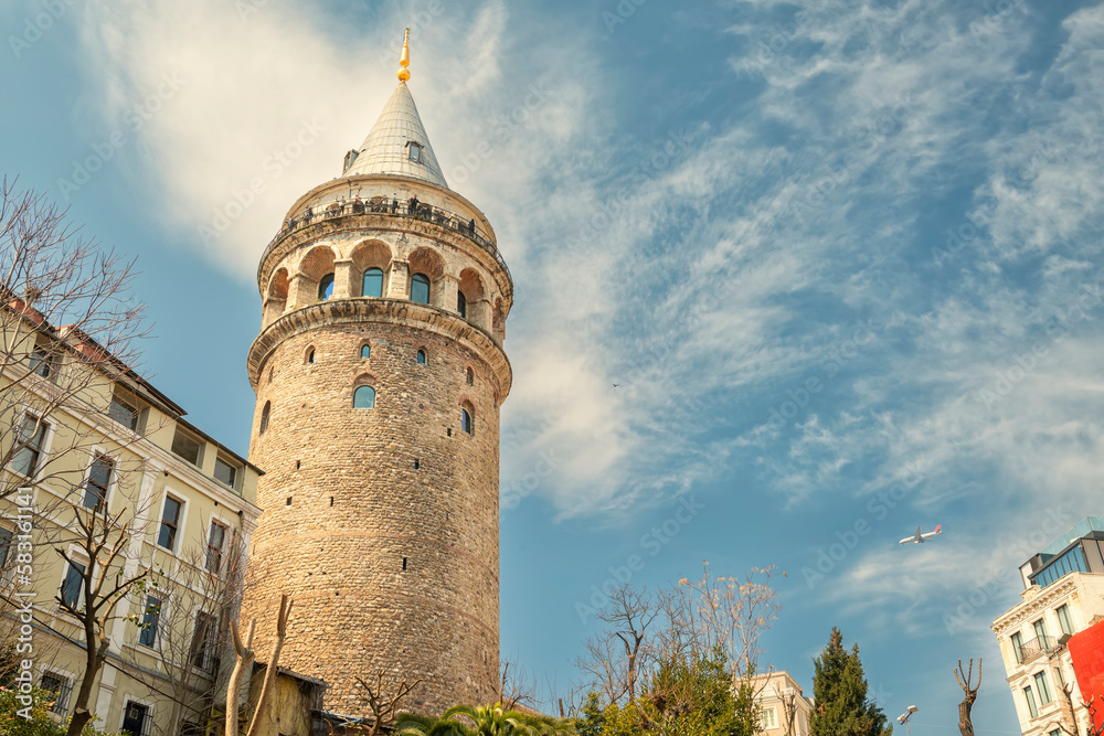 View of the Galata Tower against the sky and a flying plane. Istanbul. Turkey