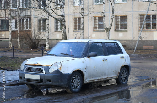 An old white rusty car is parked on the city street, Iskrovsky Prospekt, St. Petersburg, Russia, March 2023 © Станислав Вершинин