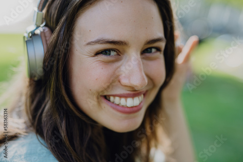 Portrait of young woman listening music trough headphones.