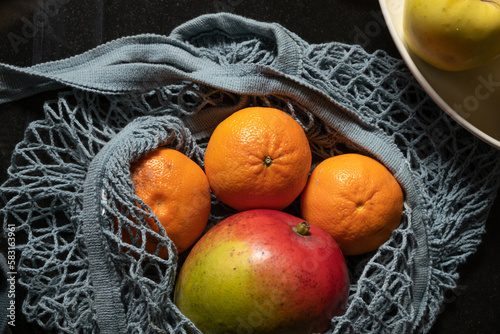 cloth bags with fresh fruit, blue bags, with tangerine, orange and mango in a kitchen
 photo