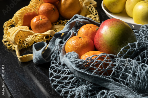 cloth bags with fresh fruit inside with tangerine, orange and mango in a kitchen
 photo