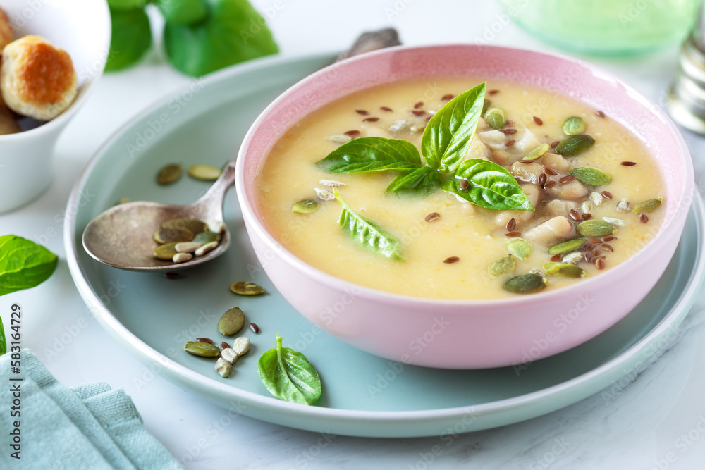 Delicious homemade Canellini bean creamy soup served with seeds and leaves of basil in a bowl