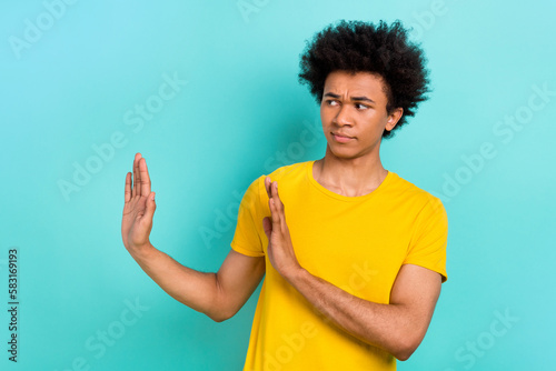 Photo of upset serious guy afro hairstyle wear yellow t-shirt look empty space rejecting offer isolated on turquoise color background