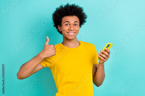 Photo of satisfied handsome guy afro hairstyle dressed yellow t-shirt showing like nice job isolated on turquoise color background