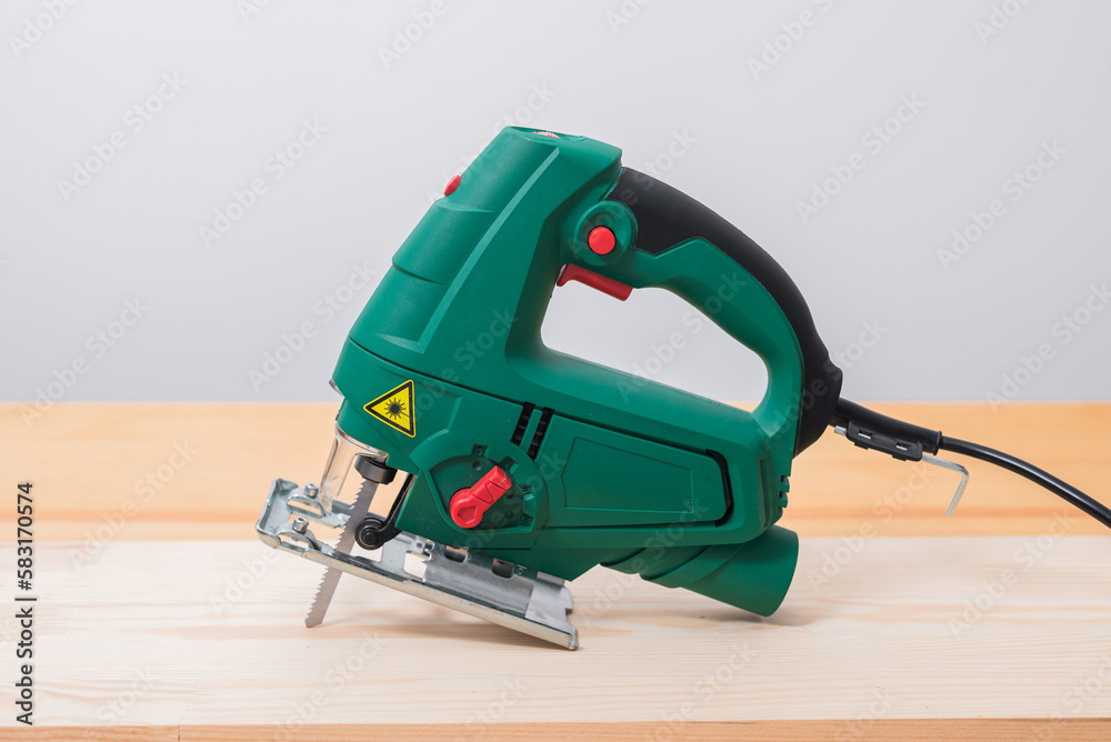 A man works with an electric jigsaw for wood on a wooden table with and without gloves and measures with a tape measure A man works with an electric jigsaw for wood on a wooden table with and without gloves and measures with a tape measure