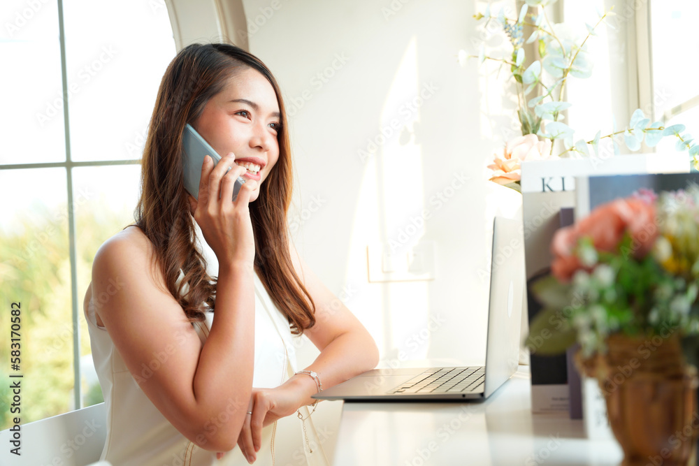 Asian woman with curly hair is working chatting with clients or colleagues via communication channels, telephone, internet with her laptop and mobile phone. Asian woman with curly hair is working chatting with clients or colleagues via communication channels, telephone, internet with her laptop and mobile phone.