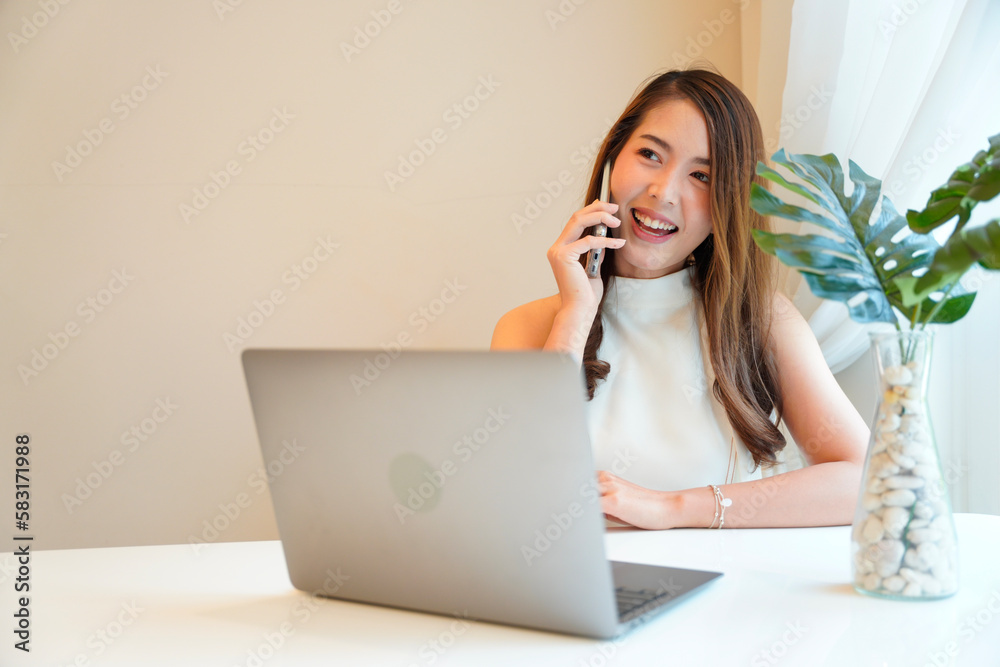 Asian woman with curly hair is working chatting with clients or colleagues via communication channels, telephone, internet with her laptop and mobile phone. Asian woman with curly hair is working chatting with clients or colleagues via communication channels, telephone, internet with her laptop and mobile phone.
