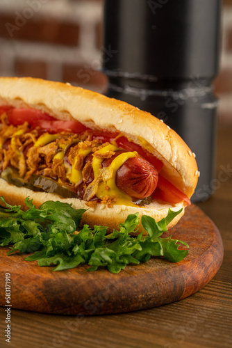 hot dog on a dark wooden background. fried sausage in sauce