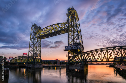 Industrial bridge terminal De Hef in Rotterdam with water reflections during sunset with clouds