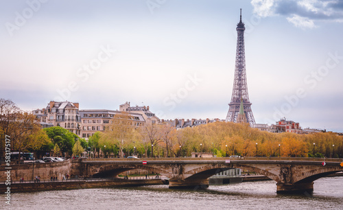 View of the Eiffel tower behind a historical bridge and houses during the day © Guniva