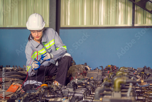 Female engineer wearing uniform Form and safety helmet inspecting repair parts in robotic arm warehouse in factory