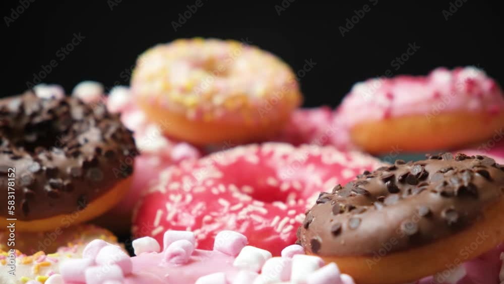 Donuts with red, pink and chocolate icing and marshmallows spin the view from above Donuts with red, pink and chocolate icing and marshmallows spin the view from above