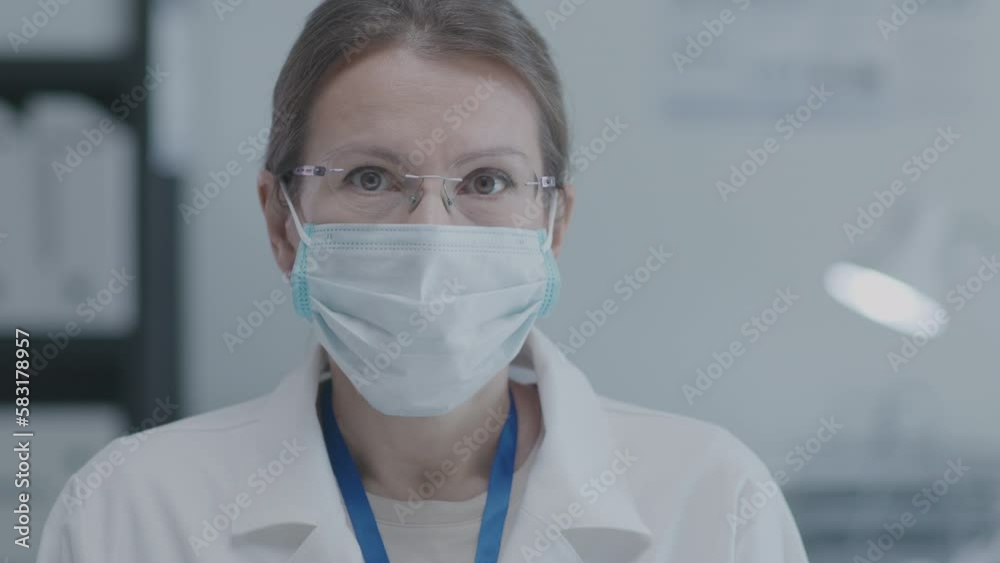 Video portrait of female doctor in medical mask looking at camera when standing in clinic Video portrait of female doctor in medical mask looking at camera when standing in clinic
