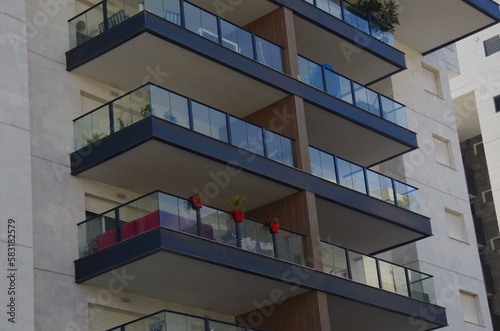 Beautiful balcony in a modern apartment building. White building against the blue sky. place for text © ShU studio