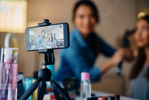 Foto Happy female friends recording hairstyle tutorial with smart phone