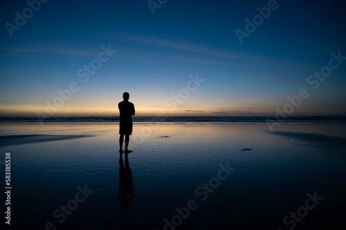 Person standing on beach with sunset