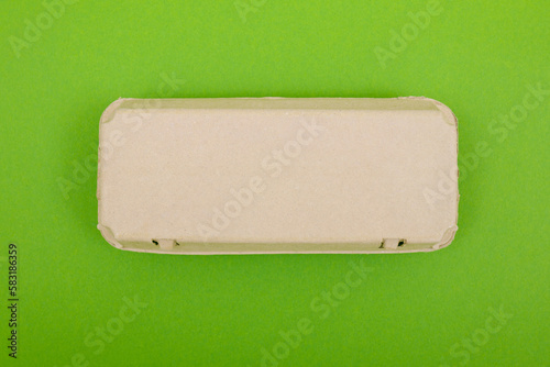 Closed egg box with ten eggs. Close carton pack or egg container top view with copy space. Egg box with chicken eggs, carton pack or egg container. Green background.