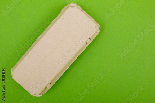 Closed egg box with ten eggs. Close carton pack or egg container top view with copy space. Egg box with chicken eggs, carton pack or egg container. Green background.