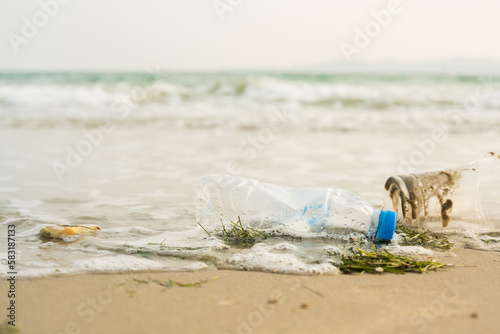 Close up plastic bottle and cup on the sand beach.Save the earth.Environment ecology care and renewable concept.Volunteer or traveller collecting plastic waste.Cleaning beach on morning time.