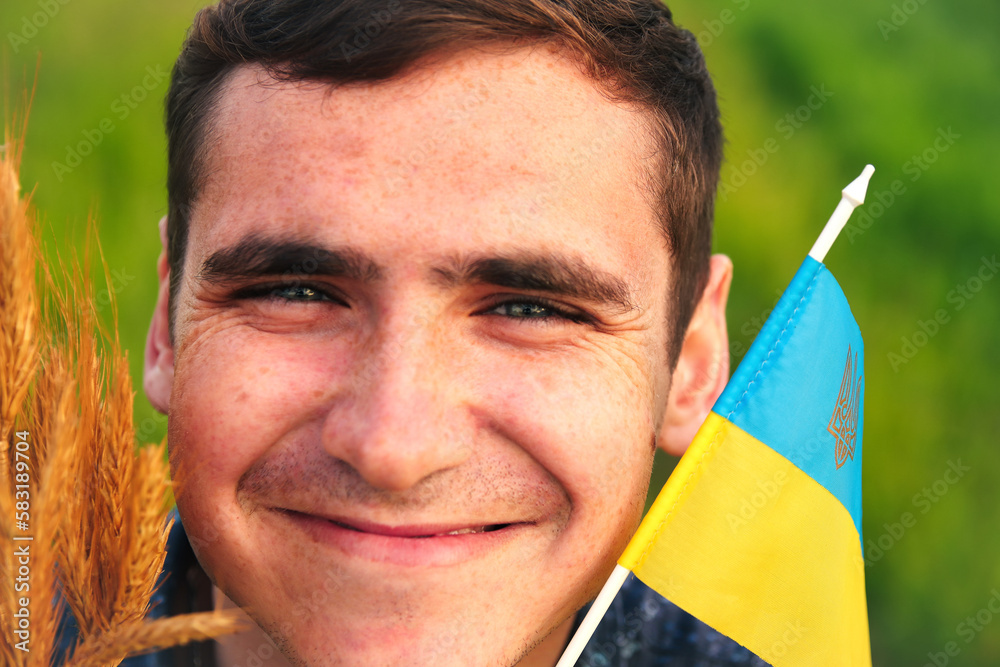 Man with flag of Ukraine outdoors. Young ukrainian men portrait. Bouquet of ripe golden