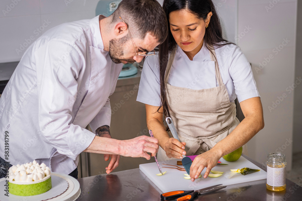 A couple of pastry chefs prepare and decorate a cake in pairs A couple of pastry chefs prepare and decorate a cake in pairs