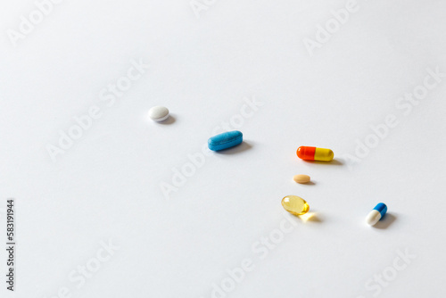 Scattered pills of different colors on a white background. Medical concept as pill addiction. A pill as a solution for everything.