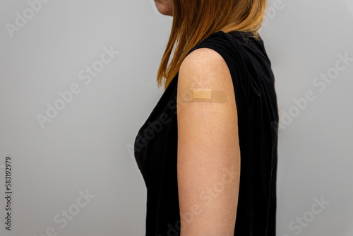 Woman shown in profile showing hand with patch. The concept of seasonal vaccination. The return of viruses. 