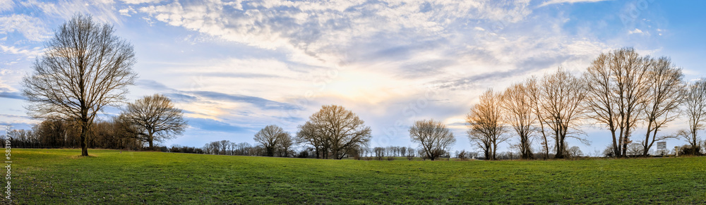 Panorama einer Landschaft mit Wiesen, Bäumen und einem blauen Himmel mit Sonne und Wolken in Loccum Panorama einer Landschaft mit Wiesen, Bäumen und einem blauen Himmel mit Sonne und Wolken in Loccum