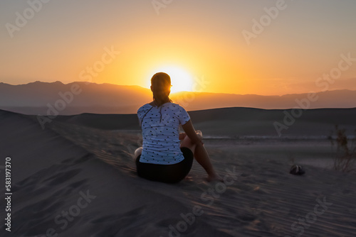 Silhouette of woman enjoying the sunrise with scenic view on Mesquite Flat Sand Dunes, Death Valley National Park, California, USA. Morning walk in Mojave desert with Amargosa Mountain Range in back. photo