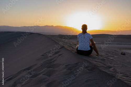 Silhouette of woman enjoying the sunrise with scenic view on Mesquite Flat Sand Dunes, Death Valley National Park, California, USA. Morning walk in Mojave desert with Amargosa Mountain Range in back.