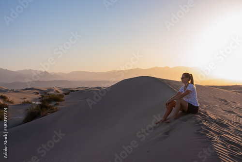Silhouette of woman enjoying the sunrise with scenic view on Mesquite Flat Sand Dunes, Death Valley National Park, California, USA. Morning walk in Mojave desert with Amargosa Mountain Range in back. © Chris